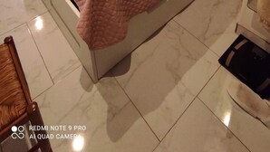 A neatly made bed in a room with a large window, a small shelf with books and a radio, and a tiled floor. - Renovated apartment in the Boucanet district near the center of Grau du Roi and La Grande Motte (Le Grau-du-Roi)