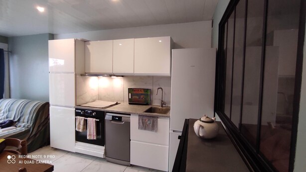 A compact kitchen with white cabinets, a built-in oven, a dishwasher, and a small sink. - Renovated apartment in the Boucanet district near the center of Grau du Roi and La Grande Motte (Le Grau-du-Roi)