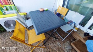 A small outdoor dining area with a table and chairs, a fan, and a window. - Renovated apartment in the Boucanet district near the center of Grau du Roi and La Grande Motte (Le Grau-du-Roi)