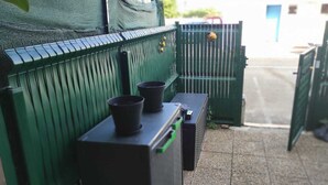 A green metal fence with a trash bin and a black object on top. - Renovated apartment in the Boucanet district near the center of Grau du Roi and La Grande Motte (Le Grau-du-Roi)