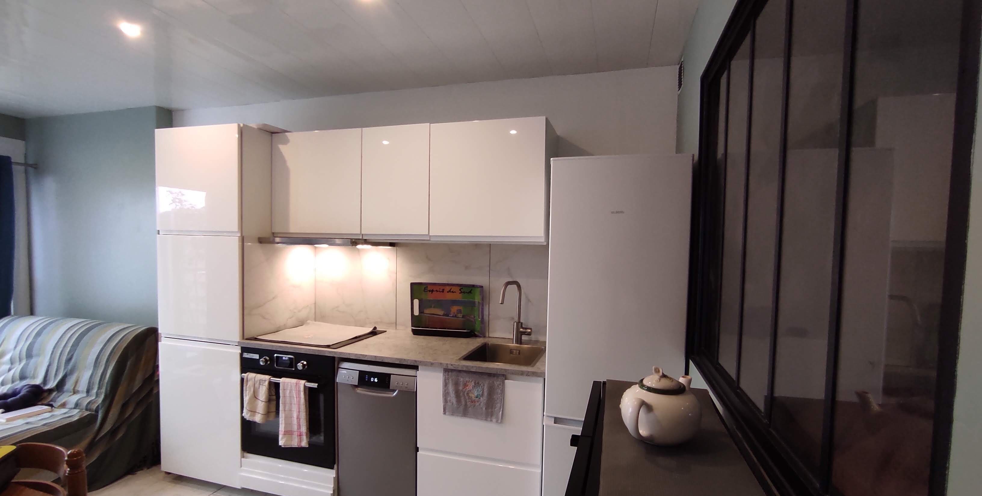 A compact kitchen with white cabinets, a built-in oven, a dishwasher, and a small sink.