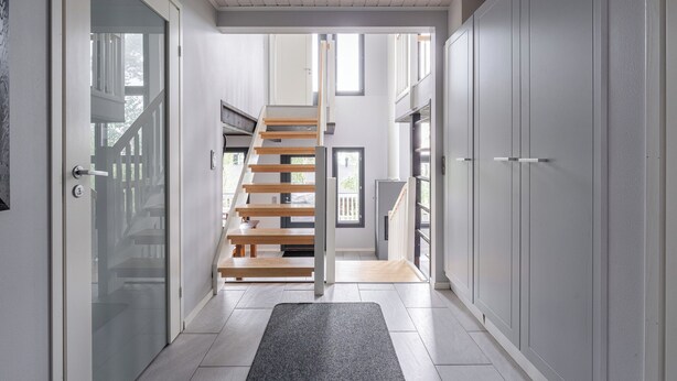 A modern interior with a staircase leading to a balcony, white walls, and a door with frosted glass. - Peaceful 2BR Getaway Cabin at Riihivuori (Muurame)