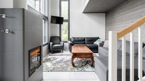 A modern living room with a fireplace, a sofa, a coffee table, and a TV mounted on the wall. - Peaceful 2BR Getaway Cabin at Riihivuori (Muurame)