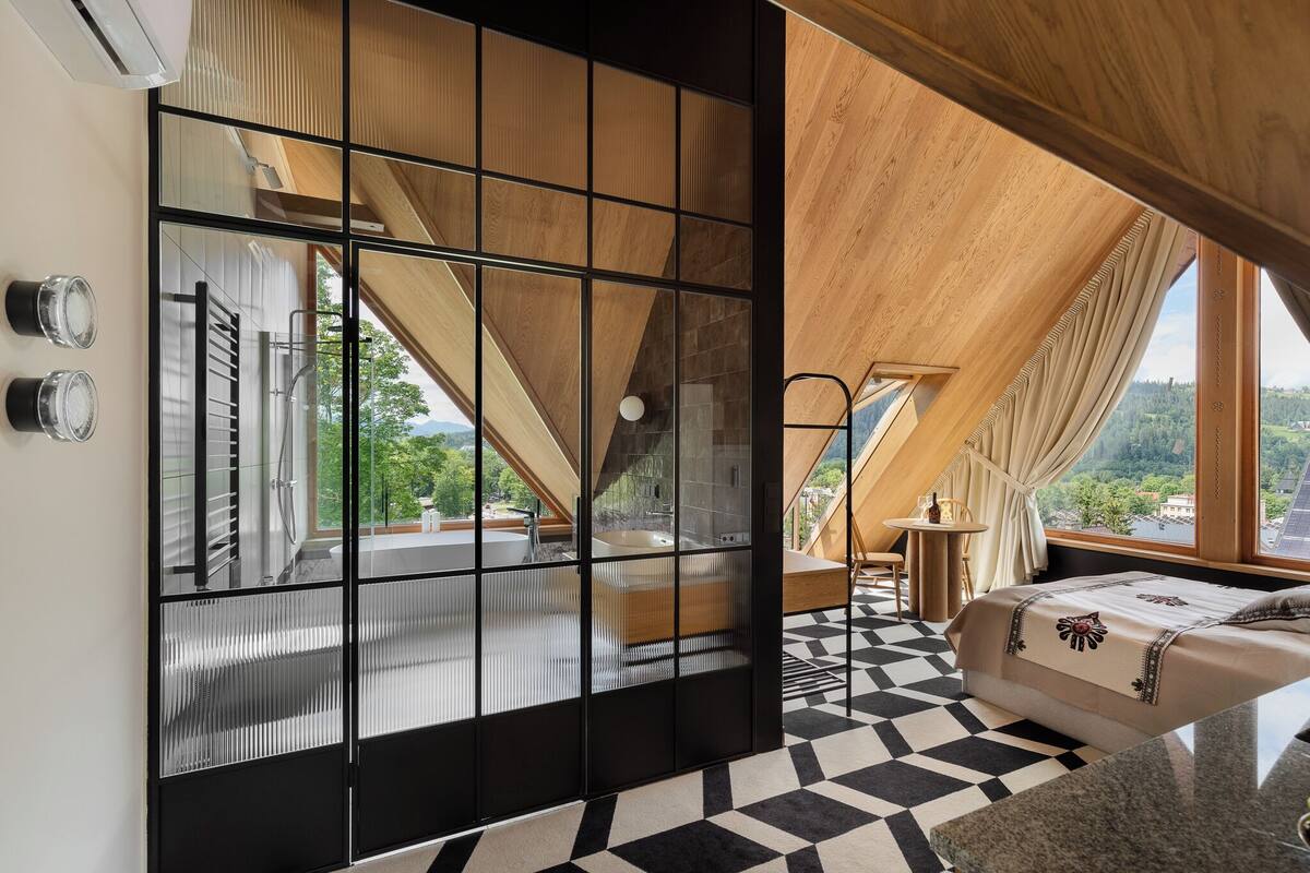 Une chambre moderne dotée d’une grande fenêtre, d’un lit, d’une petite table et offrant une vue sur l’extérieur.