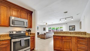A kitchen with wooden cabinets, a stainless steel microwave, and a granite countertop. - Resort Style Pool!  Large Sun-drenched Patio 1.6 miles  Poolside to Seaside! (Fort Lauderdale)
