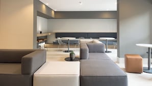 A modern lounge area with a sectional sofa, round tables, and a seating bench.