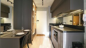 A modern kitchen with a dining area, featuring a central island, built-in appliances, and a large window providing natural light.