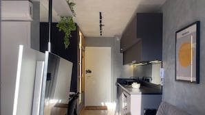 A modern kitchen with a built-in stove, a dining area with a white table and chairs, and a gray sofa in the living area.