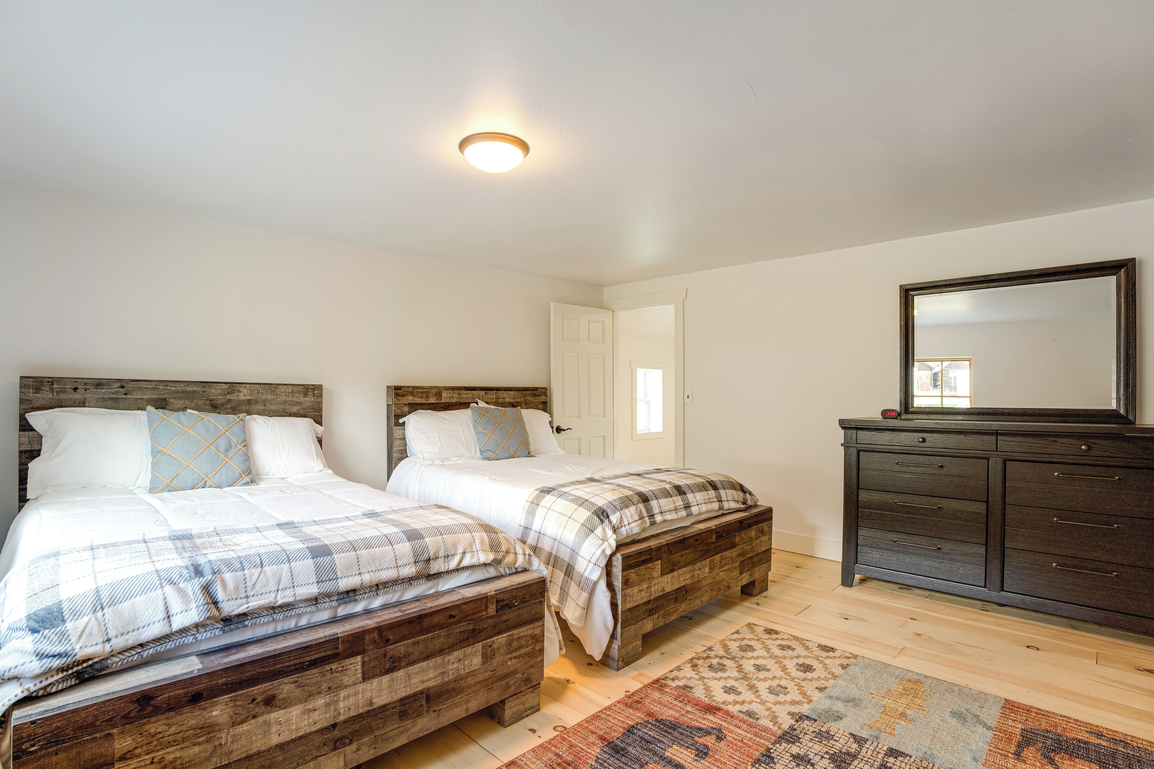 Un dormitorio con dos camas de madera, un aparador y un espejo.
