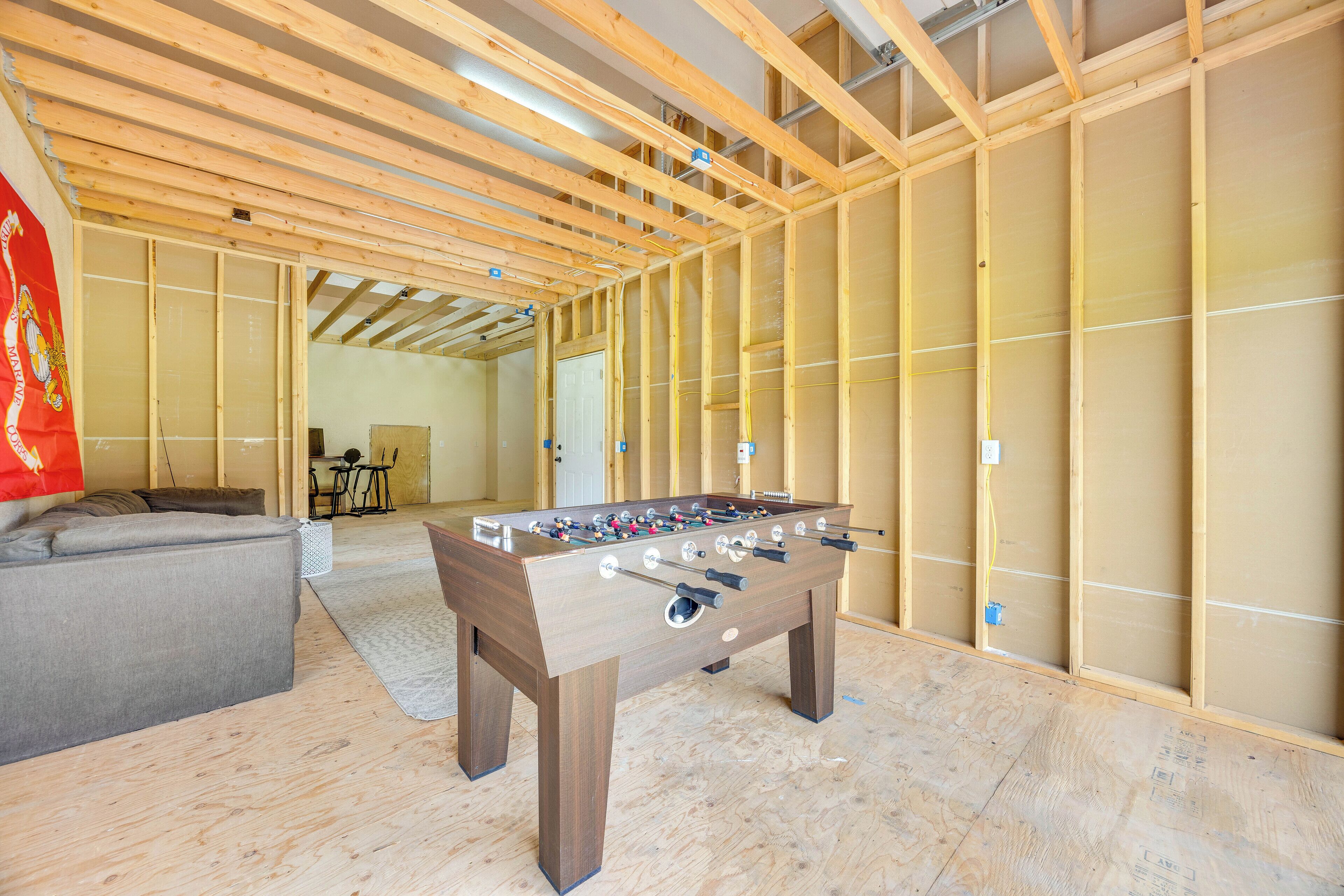 Ein Zimmer mit Tischfußball, einer Couch und einer Holzbalkenkonstruktion.