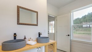 Une salle de bain avec deux grands lavabos ronds, un miroir doté d’un cadre orné et un meuble-lavabo en bois.