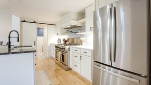 Une cuisine moderne avec des meubles blancs, des appareils en acier inoxydable et un plancher en bois.