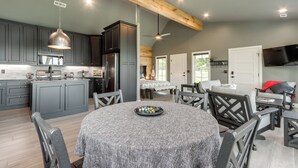 Una cocina moderna con armarios grises, una isla central y un comedor con mesa redonda y sillas.