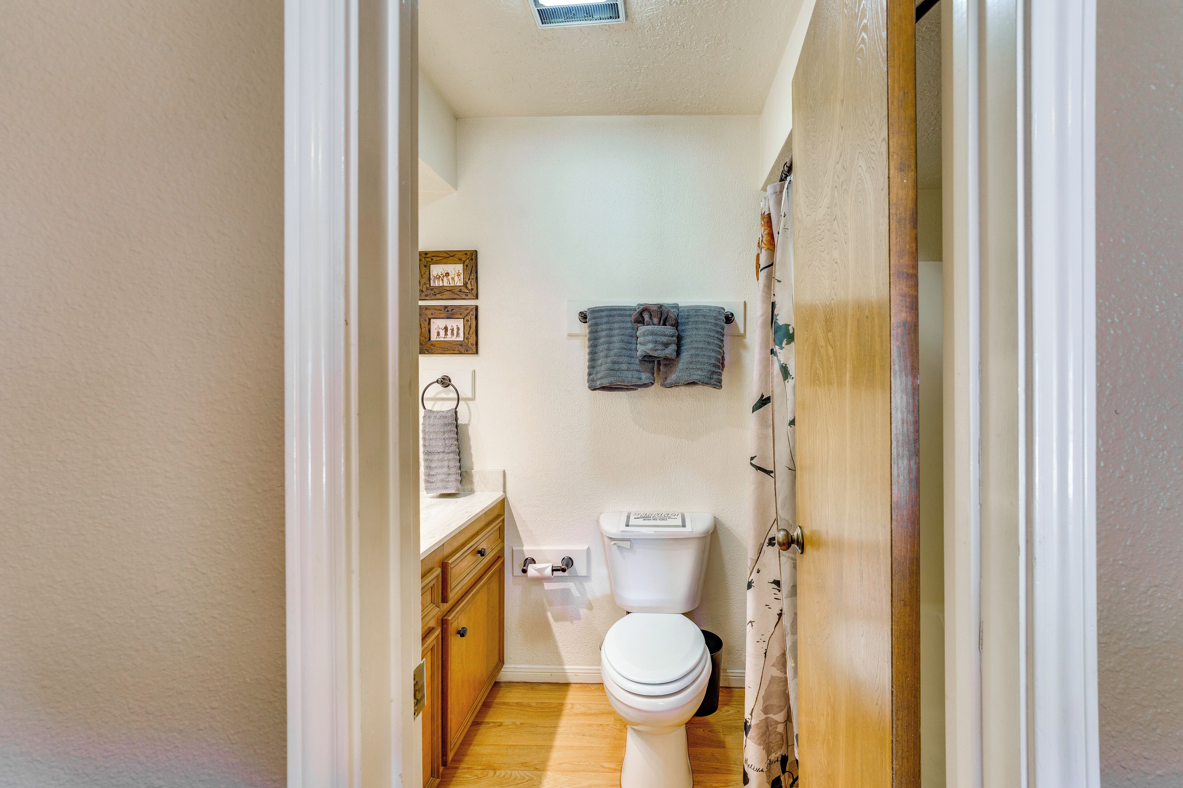 A compact bathroom with a toilet, wooden cabinet, and two towels on a rack.