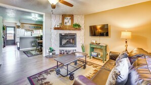 Un salon avec une cheminée, un ventilateur de plafond, un téléviseur et un canapé.