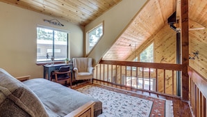 A cozy bedroom with a wooden ceiling, a large window, a desk, and a chair. - Live Like a Local in Truckee: Luxe Cabin Near Dtwn (Truckee)