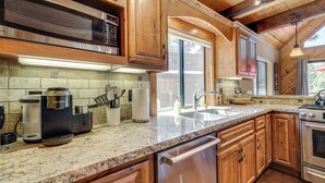 A kitchen with wooden cabinets, a stainless steel microwave, a built-in oven, and a granite countertop. - Live Like a Local in Truckee: Luxe Cabin Near Dtwn (Truckee)