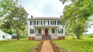 A two-story house with a red door, a front porch, and a brick pathway leading to the entrance. - Historic 30 Acre Retreat - Get Back to Nature (Ruckersville)