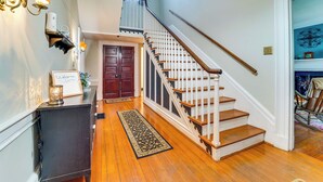 A wooden staircase with a white handrail, a dark wooden bench, and a welcome sign on the wall. - Historic 30 Acre Retreat - Get Back to Nature (Ruckersville)
