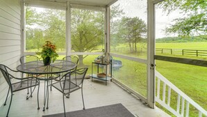 A covered porch with a table and chairs, a potted plant, and a view of a green field. - Historic 30 Acre Retreat - Get Back to Nature (Ruckersville)