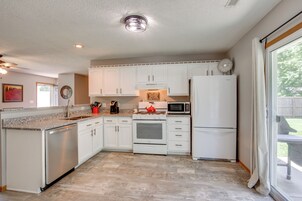 A modern kitchen with white cabinets, a stainless steel dishwasher, a microwave, and a red kettle.