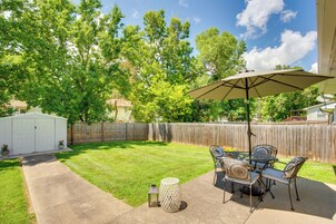 A backyard with a patio area, a white shed, and a wooden fence.