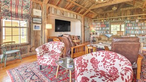 Un intérieur rustique avec des poutres apparentes, une grande bibliothèque et un téléviseur à écran plat.