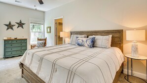 Un dormitorio con una cama grande, un ventilador de techo, un aparador y una mesita de noche.