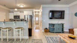 Una cocina moderna con armarios blancos, una isla central con taburetes, un microondas y un refrigerador.