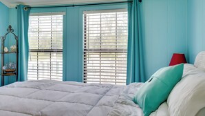 A bedroom with a bed, a window with blinds, a red lamp, and a small shelf with a ship decoration. - 'aunt Lucille's Place' - Cozy Cottage in Glenwood! (Glenwood)