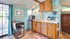 A compact kitchen with wooden cabinets, a refrigerator, a microwave, and a dining area with a table and chairs. - 'aunt Lucille's Place' - Cozy Cottage in Glenwood! (Glenwood)
