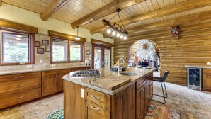 A spacious kitchen with wooden cabinets, a large island with a sink, and a stone backsplash.