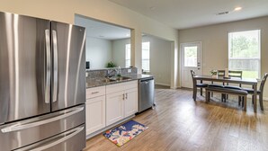 A modern kitchen with stainless steel appliances, a granite countertop, and a dining area with a wooden table and chairs. - 4 Mi to Bear Creek Pioneers Park: NW Houston Home (Houston)