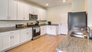 A kitchen with white cabinets, a stainless steel refrigerator, a microwave, a stove, and a granite countertop. - 4 Mi to Bear Creek Pioneers Park: NW Houston Home (Houston)