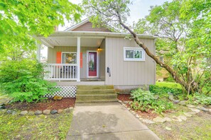 A small house with a porch, steps leading to the front door, and a garden with various plants and rocks. - Steps to Lake Huron: Retreat w/ Yard in St Ignace (St Ignace)