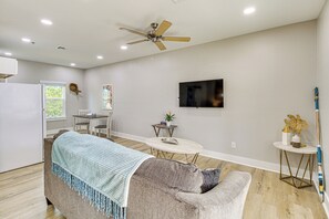 A modern living room with a sofa, a dining table, a TV, and a ceiling fan. - Fish & Swim On-site: Resort Retreat in Rockport! (Rockport)