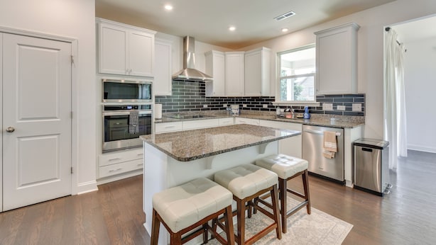 A modern kitchen with white cabinetry, granite countertops, and stainless steel appliances.