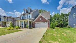 A residential area with houses featuring a mix of siding and brick exteriors, a central driveway, and well-maintained lawns.