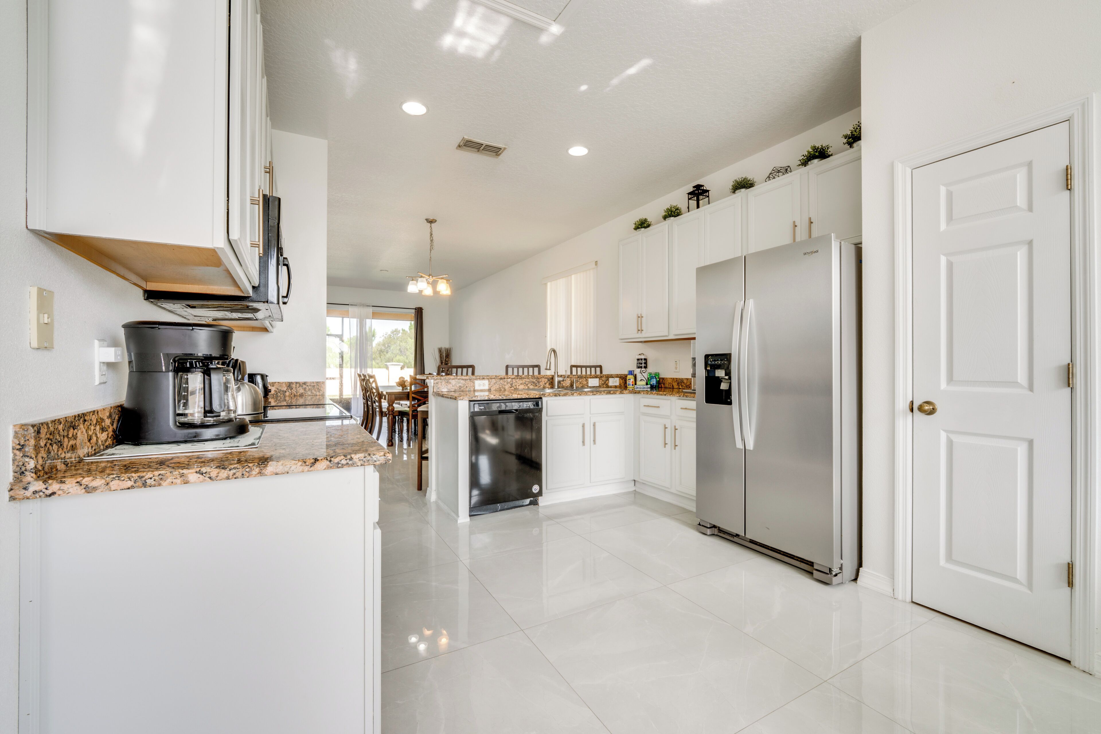 A modern kitchen with white cabinetry, stainless steel appliances, and a granite countertop.