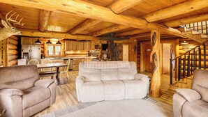 Ein Holzblockhaus-Innenraum mit einer gemütlichen Wohnbereitschaft, inklusive Sofa, Sesseln und Kamin.