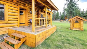 Eine Blockhütte mit Veranda, Holzstufen und einem kleinen Anbau.