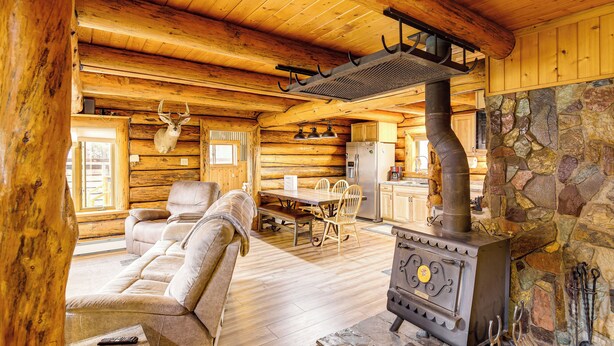 Ein Blockhaus-Interieur mit Kamin aus Stein, Holzmöbeln und einem Essbereich.