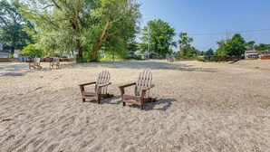 Two wooden Adirondack chairs on a sandy area with trees and a clear sky. - Walk to Private Beach: Lake Erie Retreat w/ Yard! (Huron)