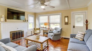 A living room with a fireplace, a ceiling fan, and a television mounted on the wall. - Walk to Private Beach: Lake Erie Retreat w/ Yard! (Huron)