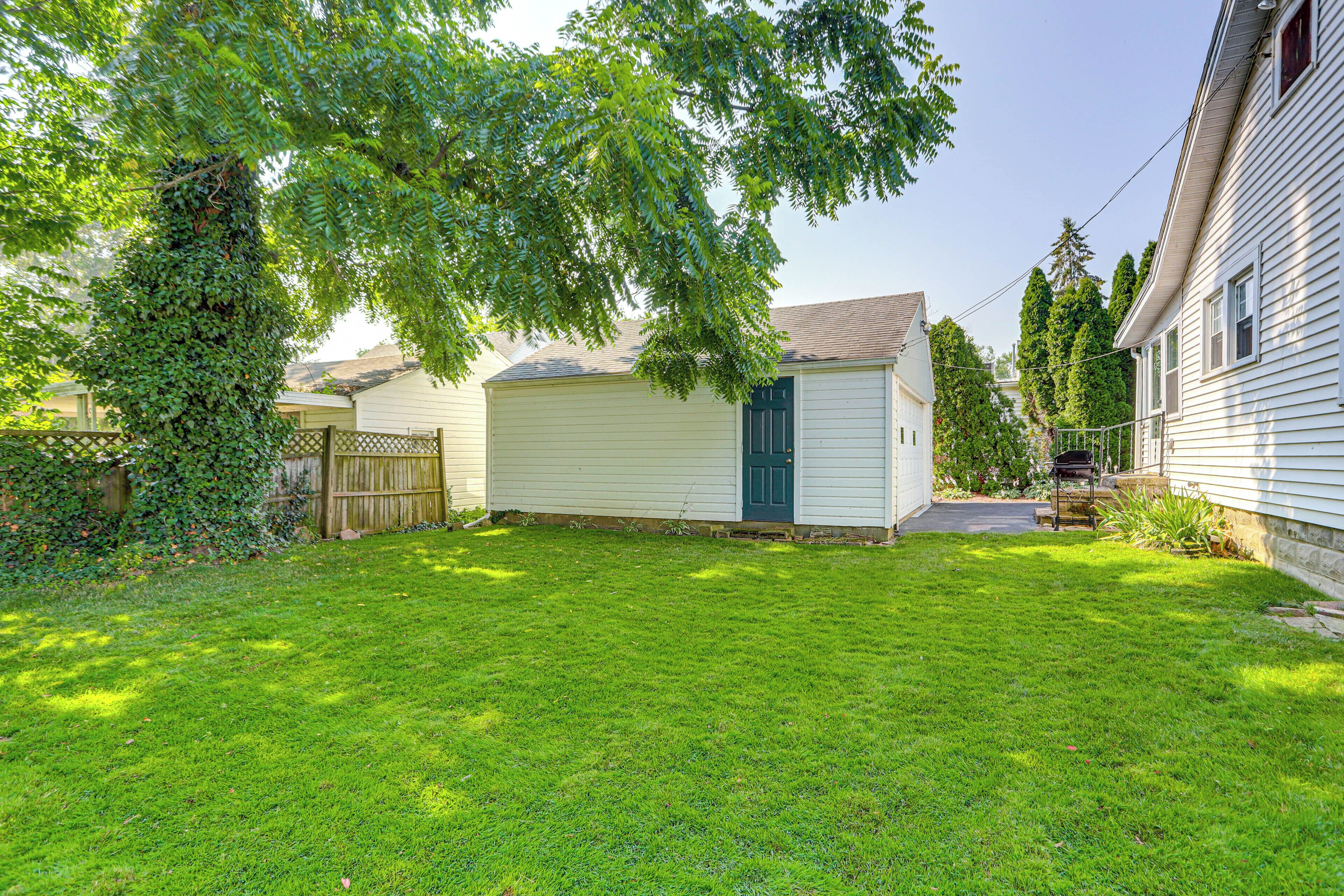 A residential property with a well-maintained lawn, a garage, and a wooden fence.