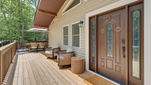 A wooden deck with outdoor furniture, a covered seating area, and a front door with glass panels. - Pool + Lake Access, Yard: Poconos Family Getaway (East Stroudsburg)