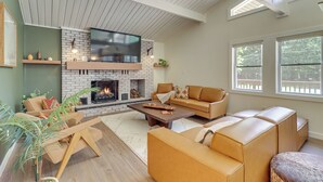 A modern living room with a fireplace, leather sofas, and a large TV. - Pool + Lake Access, Yard: Poconos Family Getaway (East Stroudsburg)