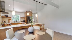 A modern kitchen with wooden cabinets, a stainless steel refrigerator, and a dining area with a round table and chairs. - Pool + Lake Access, Yard: Poconos Family Getaway (East Stroudsburg)