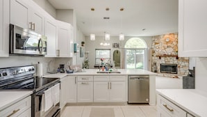 A modern kitchen with white cabinetry, stainless steel appliances, and a stone accent wall. - Jacksonville Family Home: Near Shopping & Dining! (Jacksonville)