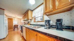 A kitchen with wooden cabinets, a white refrigerator, a coffee maker, and a window with a view of trees. - 1 Mi to Lake Access: Erie Home w/ Private Backyard (Erie)